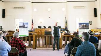 A man speaks to a group of people in a courtroom in Orleans County