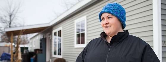A woman stands outside her modular home
