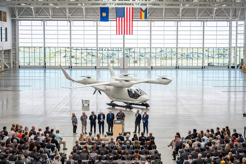 A photo of the Beta manufacturing facility's opening showing an airplane and attendees