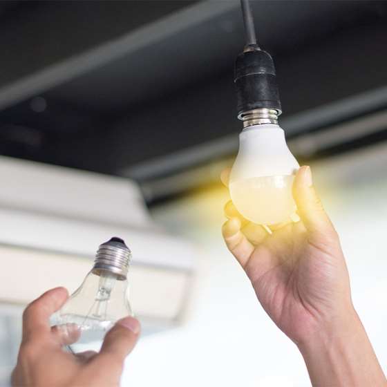 close up of a hand changing a lightbulb in a hanging fixture