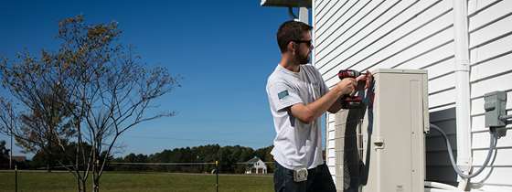 A contractor installs the external portion of a heat pump