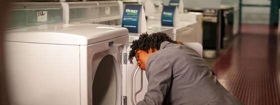 a black woman shops for laundry appliances in a retail store