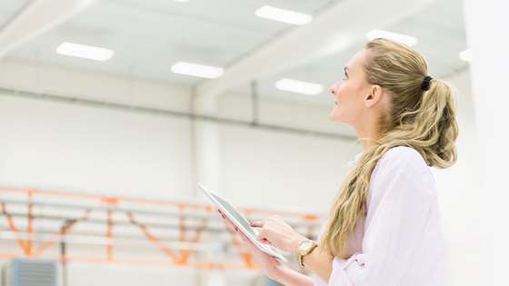 blond professional woman holding a notebook looking at lighting in an office setting