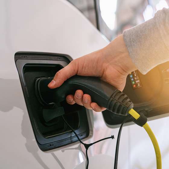 A hand plugs in an electric car