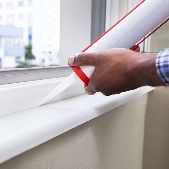 Someone adding caulk around a window frame