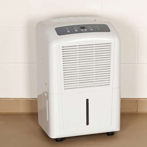A dehumidifier sitting near a painted cinderblock wall