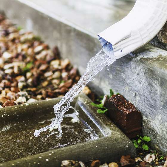A gutter spouting water out into a stone drain