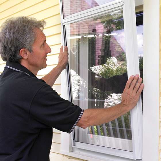 A man installs a storm window