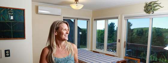 A woman stands holding a glass in front of a heat pump