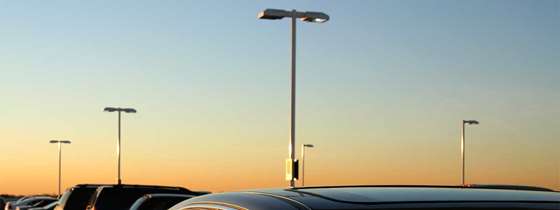 Sunset above a car dealership parking lot with parking lot lights 