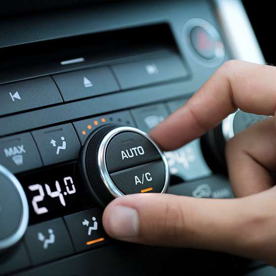 a hand reaches for the heat/ air conditioning dial on the dashboard of a car