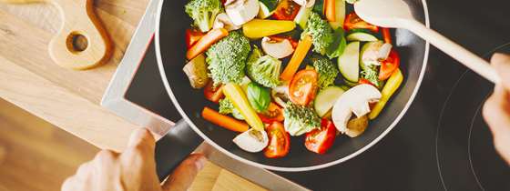 flat cooktop with sauté pan full of colorful vegetables