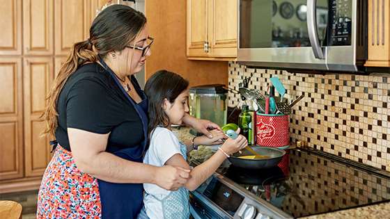 woman and child in front of an induction range in aprons