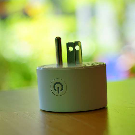 A white electric plug with a wi-fi symbol in foreground of a blurry colorful background
