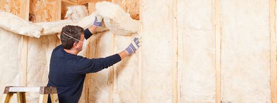 A man installs insulation in a home