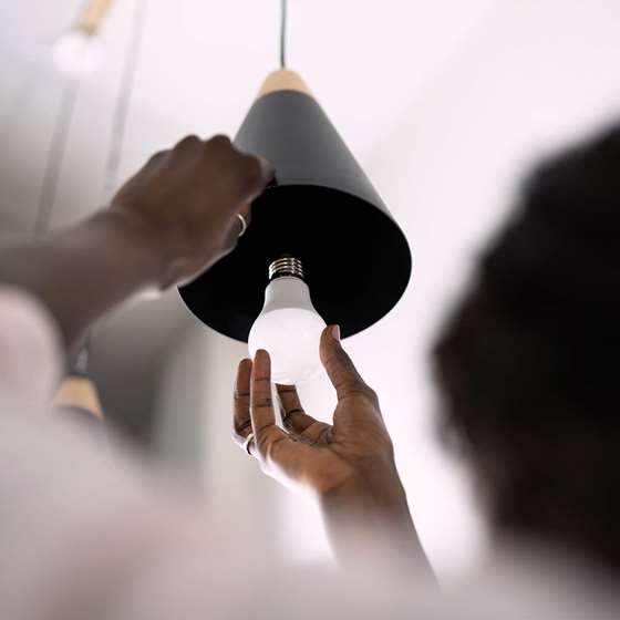 hanging light fixture bulb being replaced with LED light bulb
