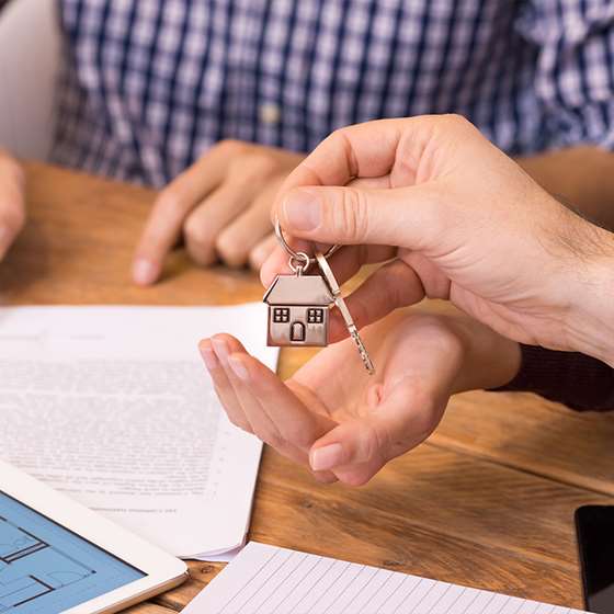 Image of person signing a mortgage and being handed a set of house keys