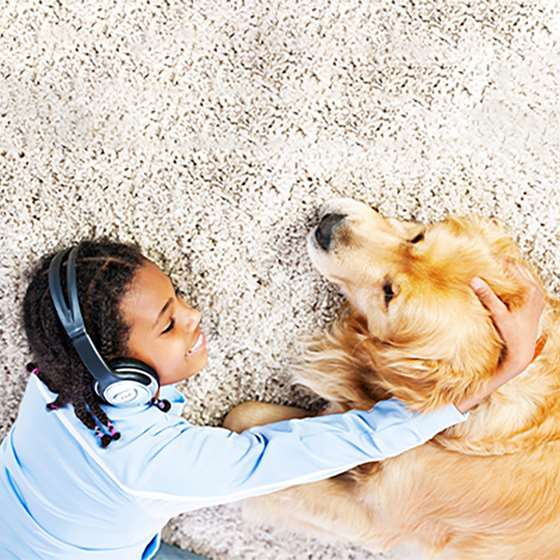 young kid on a rug in headphone with a dog