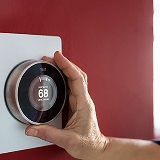 a hand near a round digital/smart thermostat