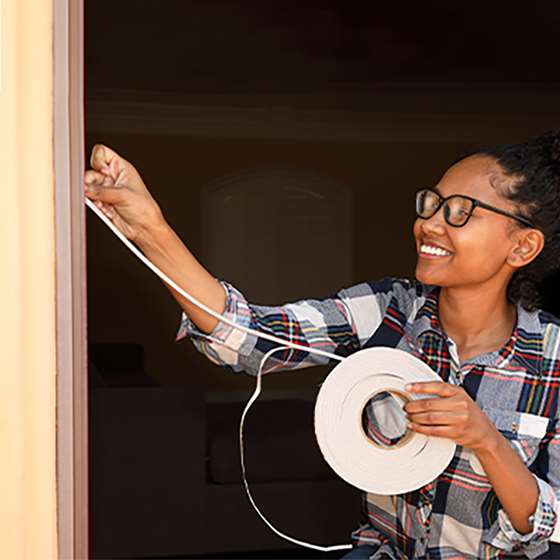 young woman standing near a door with weatherstripping materials in hand