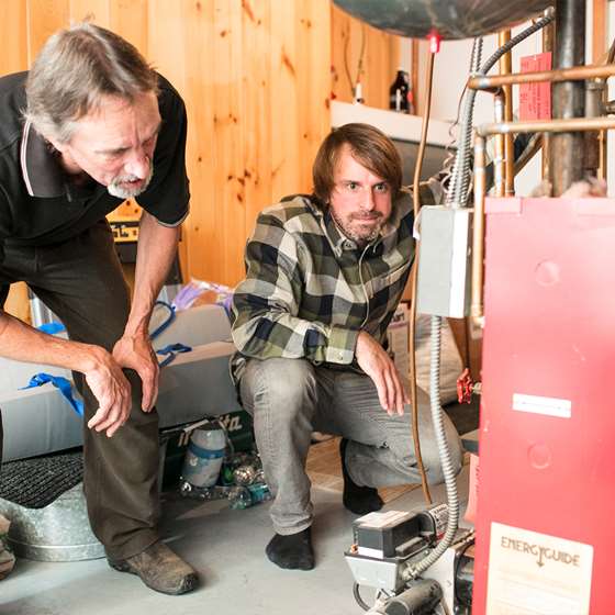 Image of two people examining a furnace or boiler