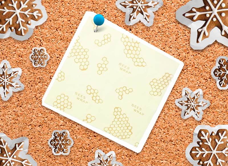A corkboard with a picture of a Bee's Wrap and snowflakes pinned to it