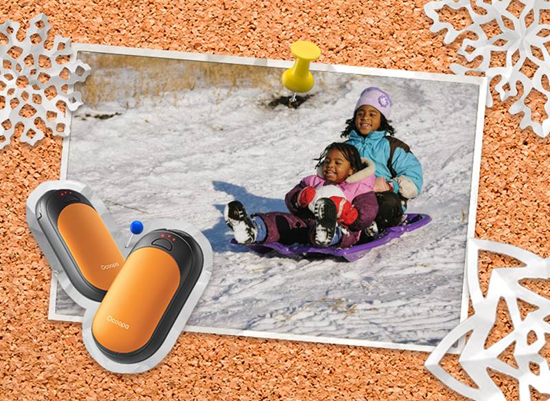A corkboard with a picture of kids sledding on an inflatable tube and a picture of handwarmers tacked to it