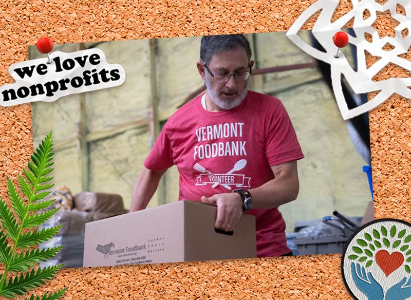 A corkboard with a pinned picture of somebody helping carry a box at a food shelf and pinned stickers about supporting nonprofits