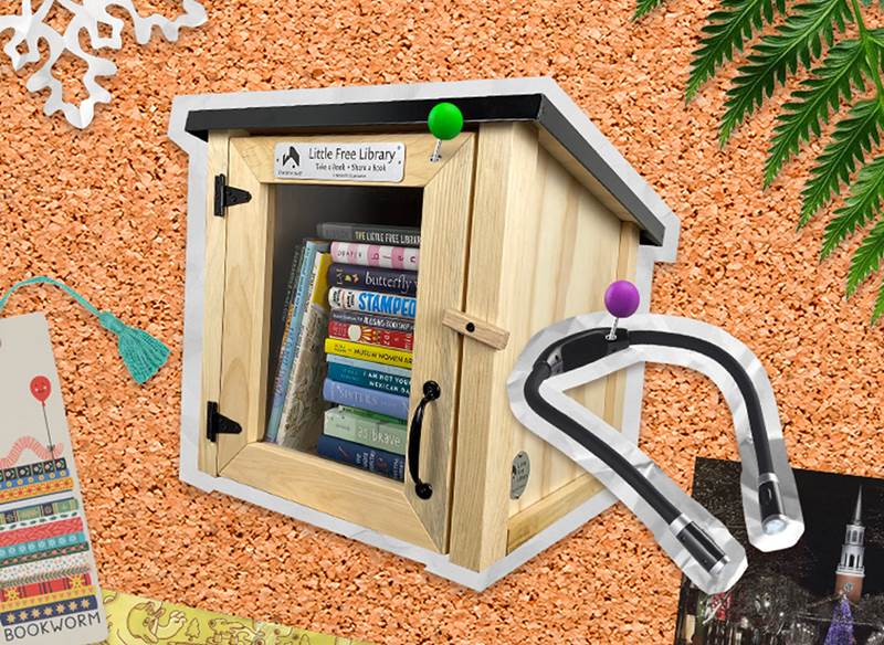 A corkboard with a picture of a little library and LED reading light pinned
