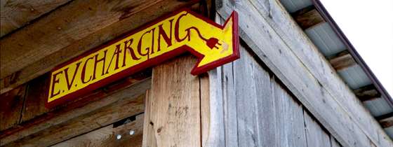 handmade wooden sign painted yellow and red, hanging in a barn that says E.V. changing with an arrow pointing down
