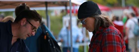 Efficiency Vermont Community Manager Brad Long speaks with a female woman across a table at an outdoors event.