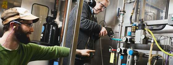 Two men test equipment in a brewery