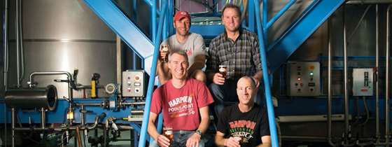 The brewers at Harpoon Brewery sit on stairs holding beer