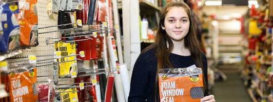 A woman holds a package of weatherstripping in a hardware store