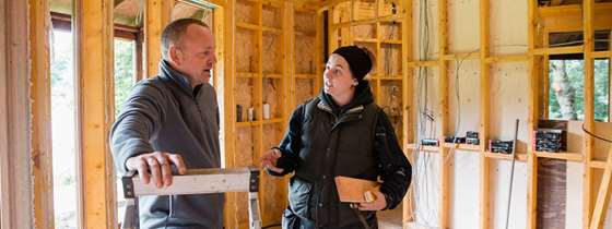 A white male speaks with a white female on a construction site