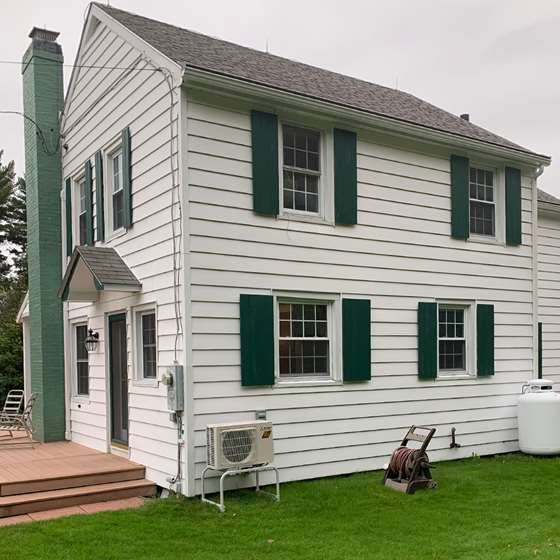 white colonial style home with heat pump