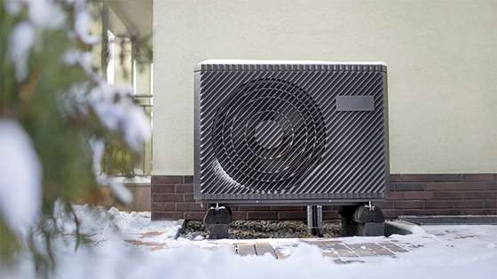 a heat pump compressor outside in light snow