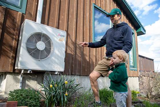 man and small child outside a home near a heat pump compressor