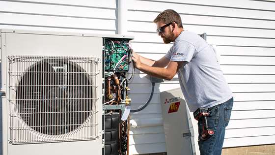 white male technician working on exterior heat pump compressor
