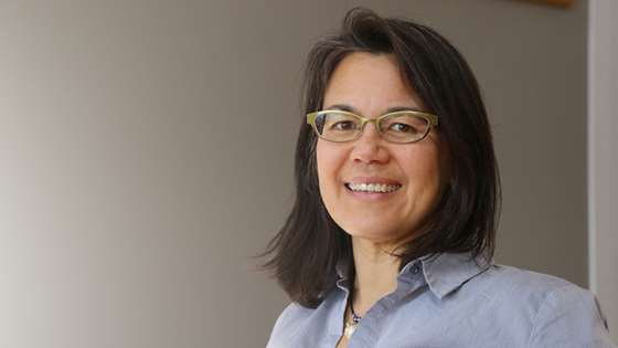 Asian American woman smiling with glasses and a blue collared shirt 