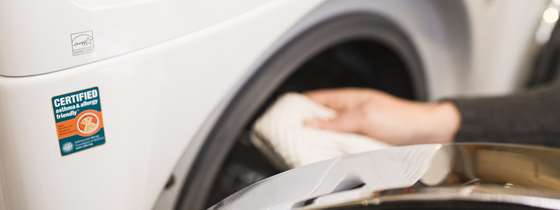 close-up of a hand putting clothing into an ENERGYSTAR clothes dryer
