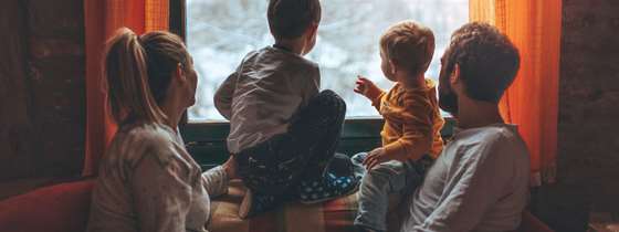 A family looks out the window at a snowy scene