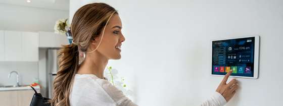 Woman in home adjusts her smart thermostat