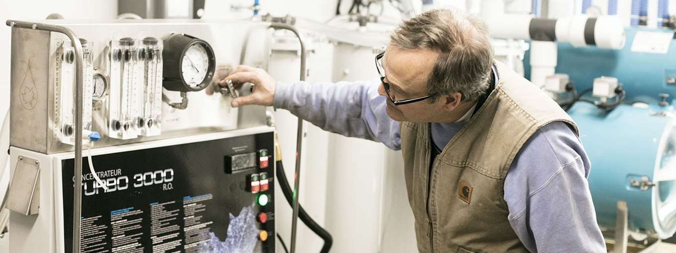 A sugarmaker bends over his equipment