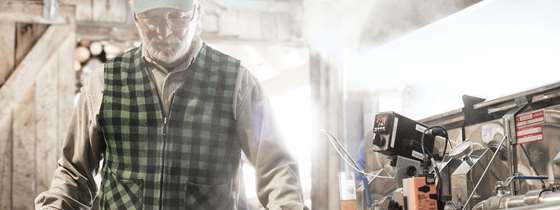 A sugar maker stands in steam in front of boiling sap