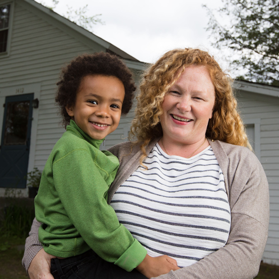 woman and child stand in front of their home