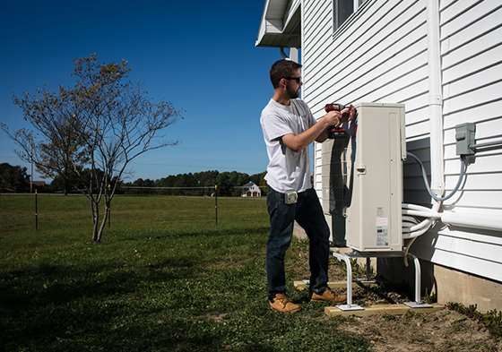 a male worker is examoning a outdoor compressor for a mini-split 