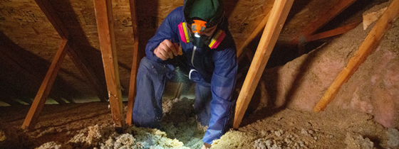 man measuring insulation in an attic space during a renovation