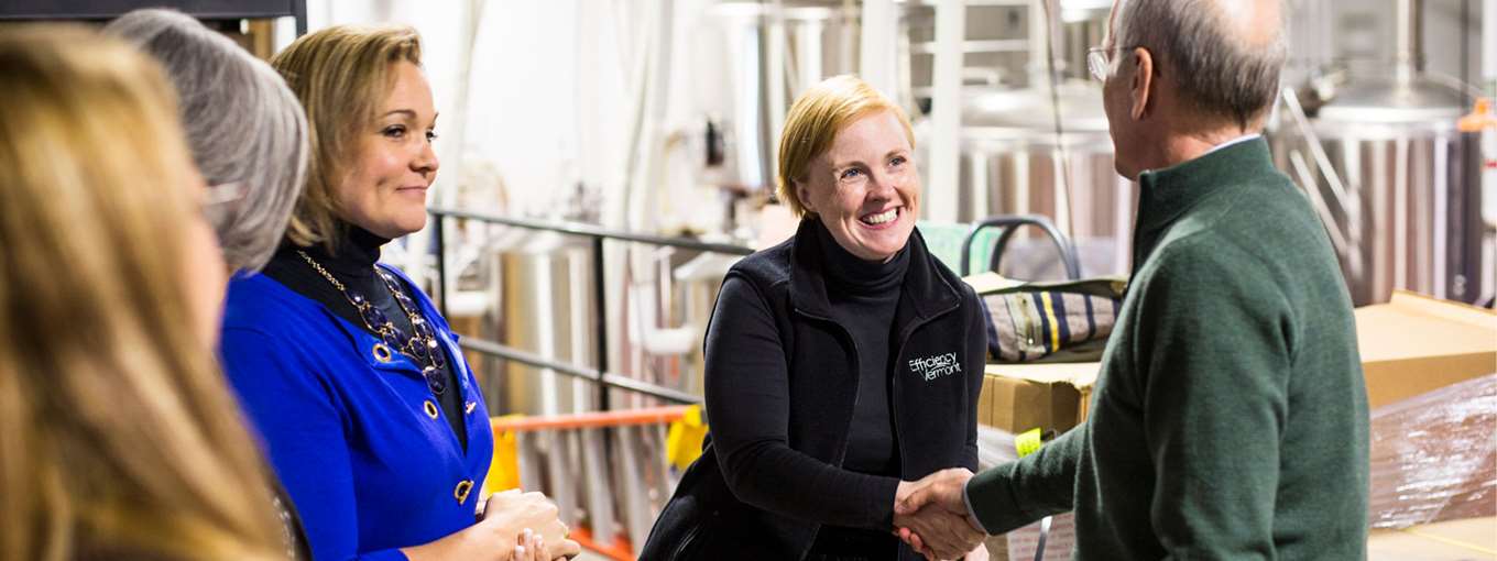 An Efficiency Vermont employee shaking hands with a customer at 14th Star Brewery
