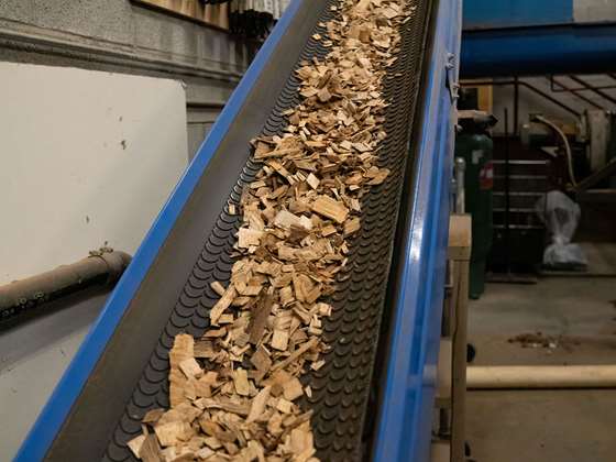blue metal conveyor belt with wood scraps used for biomass heating